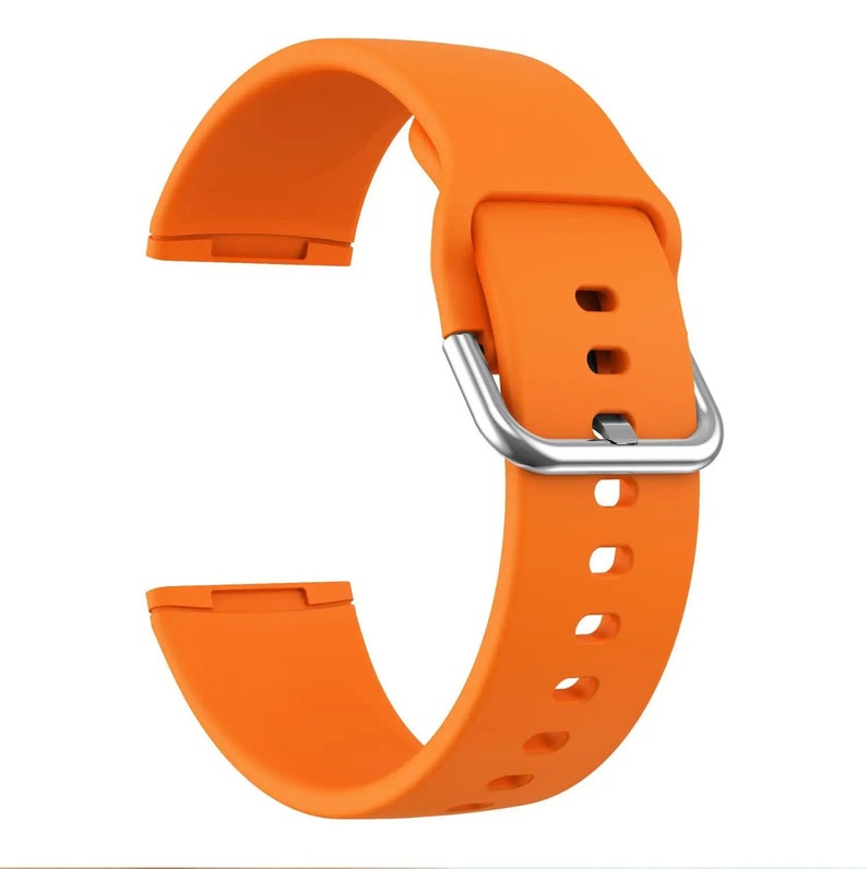 May include: Orange silicone watch band with a silver buckle. The band has multiple holes for adjusting the fit.