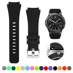May include: A black silicone watch strap with a diagonal ribbed texture, featuring a silver-toned metal buckle and a quick-release pin mechanism. The strap is shown alongside a black smartwatch with a round analog-style face displaying the date.