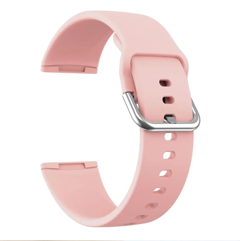 May include: A light pink silicone watch band with a silver buckle. The band has a textured surface and is designed for a smartwatch.