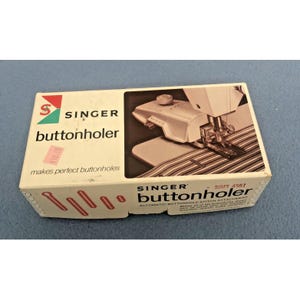 May include: A Singer buttonholer box with the Singer logo in red and green. The box features an image of a sewing machine and the text "buttonholer" and "makes perfect buttonholes".