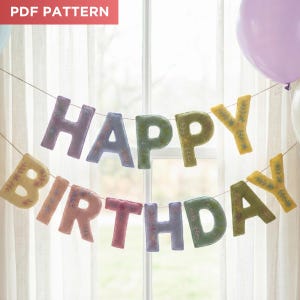 Puede incluir: Una colorida guirnalda de "Feliz Cumpleaños" hecha de fieltro, colgada frente a una ventana. Las letras son de varios colores pastel, con bordados florales. Una etiqueta "PDF PATTERN" está en la esquina superior izquierda. Se ven globos en el fondo.