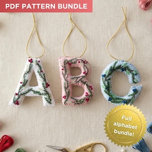 May include: Three felt letter ornaments A, B, and C with embroidered pine branches and berries, each with a gold hanging cord. The text PDF PATTERN BUNDLE appears at the top, and a gold seal with the text Full alphabet bundle! is at the bottom.