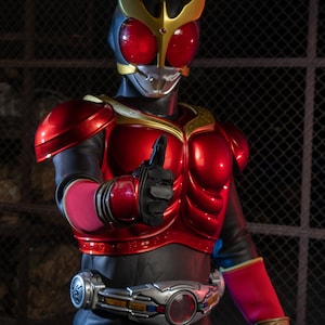 May include: A red and black superhero costume with gold accents. The helmet has a gold crest and red eyes. The figure is giving a thumbs-up gesture. The costume includes a silver belt with a red center.