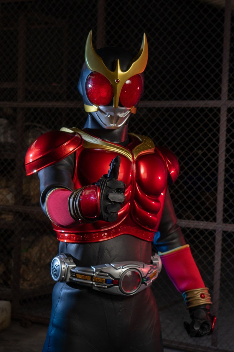 May include: A red and black superhero costume with gold accents. The helmet has a gold crest and red eyes. The figure is giving a thumbs-up gesture. The costume includes a silver belt with a red center.