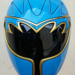 Op de afbeelding: Een blauwe en gouden Power Rangers helm met een zwart vizier. De helm heeft een kroonontwerp op de bovenkant.
