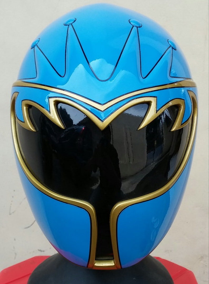 Op de afbeelding: Een blauwe en gouden Power Rangers helm met een zwart vizier. De helm heeft een kroonontwerp op de bovenkant.
