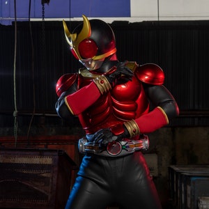 May include: A red and black superhero costume with gold accents. The costume features a helmet with gold horns, a red chest plate, and black gloves. The belt has a circular buckle with a colorful design. The suit is made of a shiny material.