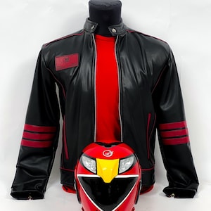 May include: A black leather jacket with red accents and a matching red helmet. The jacket has red stripes on the sleeves and a small red patch on the chest. The helmet is red with yellow and black details, and has a visor.