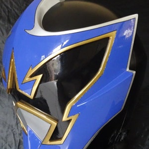 Op de afbeelding: Een blauwe en zwarte helm met gouden en zilveren accenten. De helm heeft een scherp, hoekig ontwerp met een vizier.