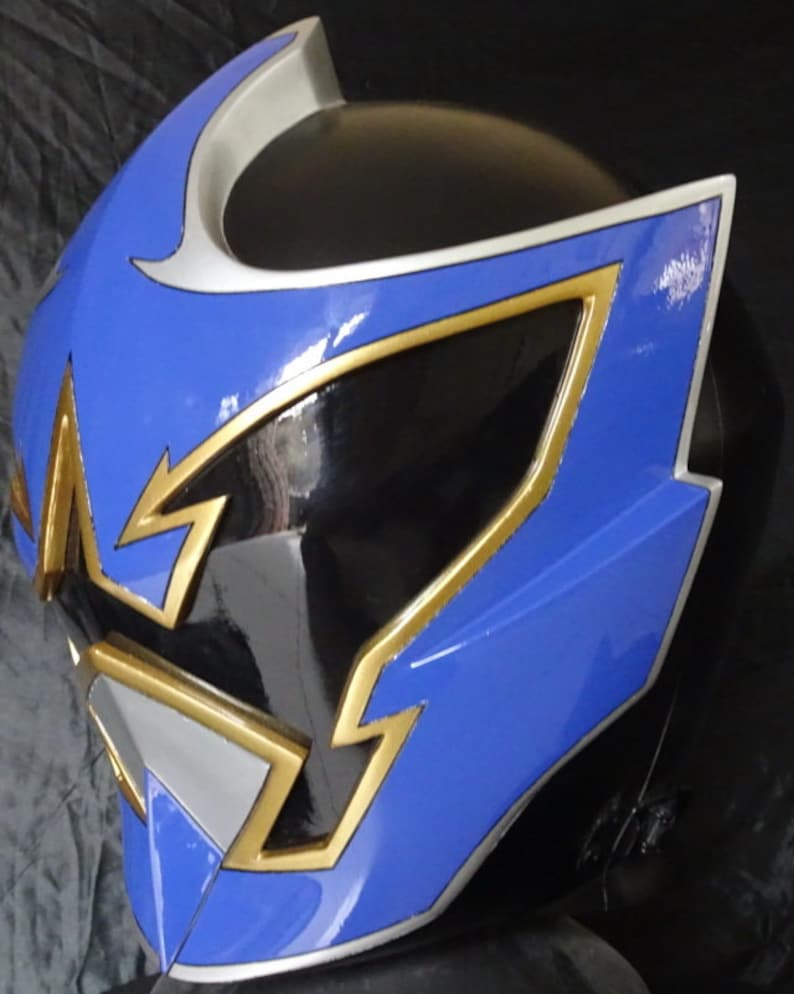 Op de afbeelding: Een blauwe en zwarte helm met gouden en zilveren accenten. De helm heeft een scherp, hoekig ontwerp met een vizier.