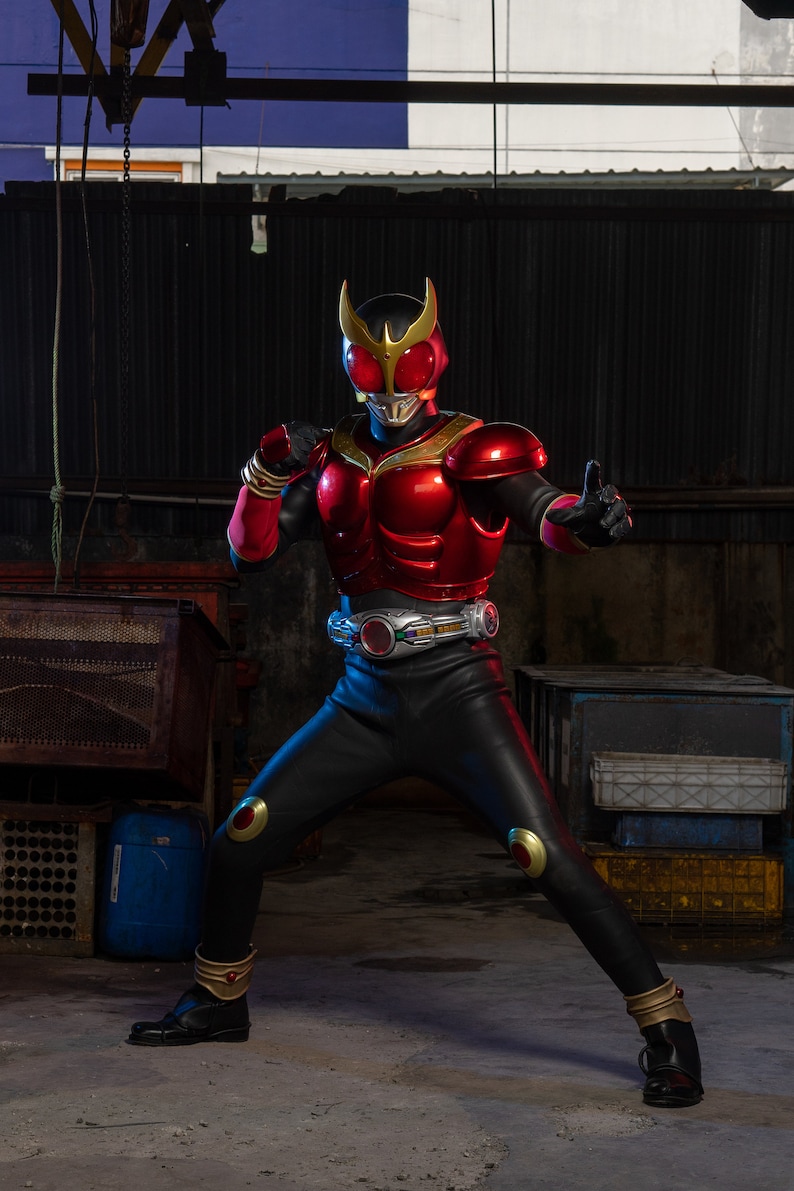 May include: A red and black superhero costume with gold accents. The costume features a helmet, chest armor, and black pants. The superhero is in a fighting stance, with one hand raised in a fist and the other in a thumbs-up gesture.