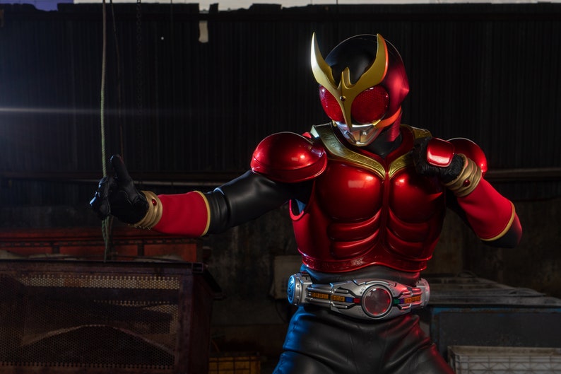 May include: A red and black superhero costume with a gold helmet and accents. The costume features a detailed chest plate, gloves, and a belt. The character is in a fighting stance, set against an industrial background.