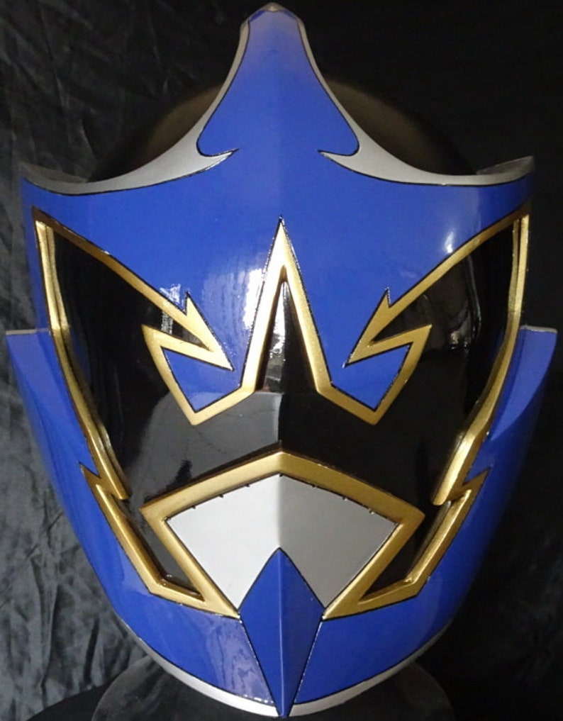 Op de afbeelding: Een blauwe en zwarte helm met gouden accenten. De helm heeft een scherp, hoekig ontwerp met een puntige bovenkant.