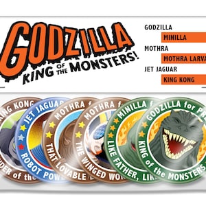 May include: A set of six round button pins featuring characters from the Godzilla franchise. The pins are green, brown, and blue with white and yellow accents. The pins feature images of Godzilla, King Kong, Jet Jaguar, and Mothra. The text on the pins reads "Godzilla for President", "King of the Monsters", "8th Wonder of the World", "That Lovable Power", "The Winged Wonder", and "Like Father, Like Son".
