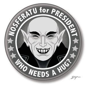May include: A black and white button with a portrait of a vampire with the text "NOSFERATU for PRESIDENT WHO NEEDS A HUG?" around the edge.