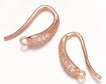 May include: A pair of rose gold earring hooks with clear cubic zirconia stones.