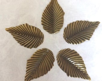 Op de afbeelding: Vijf goudkleurige metalen bladeren met een geribbelde textuur.