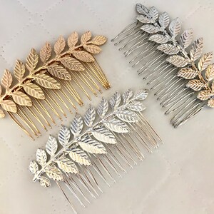Op de afbeelding: Drie gouden en zilveren haar kammen met een blad ontwerp. De kammen zijn gemaakt van metaal en hebben een delicate, vrouwelijke uitstraling.