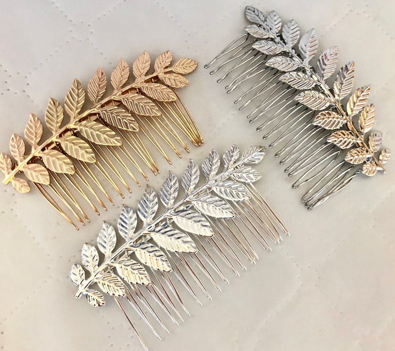 Op de afbeelding: Drie gouden en zilveren haar kammen met een blad ontwerp. De kammen zijn gemaakt van metaal en hebben een delicate, vrouwelijke uitstraling.