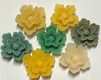 May include: Six resin flower embellishments in shades of yellow, green, and cream. The flowers are layered and have a three-dimensional appearance.