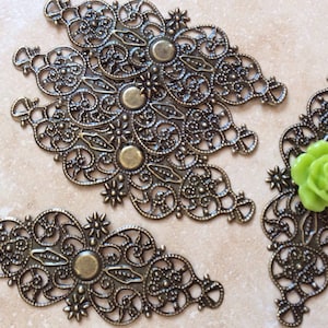 May include: Four antique gold filigree metal embellishments with a green glass rose in the center of one.