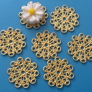May include: Six gold metal filigree embellishments with a daisy-shaped design. The embellishments are approximately 1 inch in diameter.