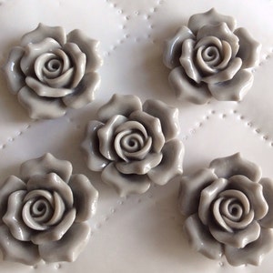 May include: Five gray ceramic rose flower embellishments. Each rose has a raised, detailed design.