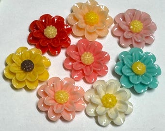 Könnte beinhalten: Sortiment von acht bunten, blumenförmigen Harz-Cabochons. Die Cabochons sind in den Farben Gelb, Rosa, Rot und Blau gehalten. Jeder Cabochon hat ein erhabenes Blumendesign mit einem Mittelkreis.