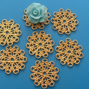 May include: Six gold metal filigree embellishments with a light blue flower embellishment in the center.