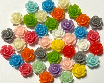 May include: A collection of small, colorful rose-shaped embellishments in various shades, including red, pink, yellow, green, blue, orange, purple, white, and gray. These decorative resin flowers are ideal for crafting and adding a floral touch to various projects.