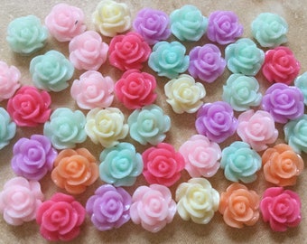 May include: Assortment of pastel colored plastic rose flower embellishments. The roses are in various shades of pink, blue, yellow, and orange.