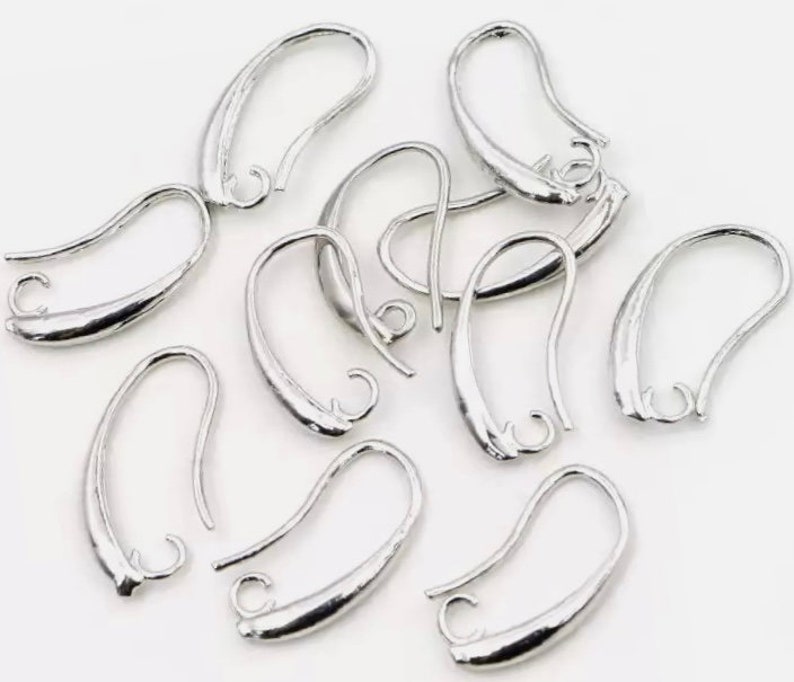 May include: Silver-toned earring hooks with a smooth, slightly curved design. The hooks are designed for attaching earrings to jewelry findings.
