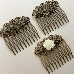 May include: Three antique bronze hair combs with ornate filigree designs. Two combs feature a central oval design, while the third has a white rose accent. The combs have multiple tines for securing in hair.