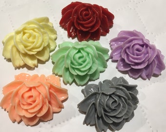 May include: Six decorative rose-shaped embellishments in various colors, including red, yellow, green, purple, peach, and gray. The roses are made of a smooth, glossy material and have a realistic appearance.