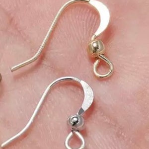 May include: Two earring hooks, one gold and one silver, with a small ball at the top and a loop at the bottom.