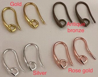 Op de afbeelding: Acht metalen oorbelhaken gerangschikt in vier paren, gelabeld Gold, Antique bronze, Silver en Rose gold. Elke haak heeft een gebogen draadontwerp met een kleine cirkelvormige lus aan de basis voor het bevestigen van sieradenonderdelen.