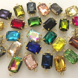 May include: Assortment of colorful glass rectangular beads with gold metal loops. The beads are in various colors, including red, blue, green, yellow, and pink.