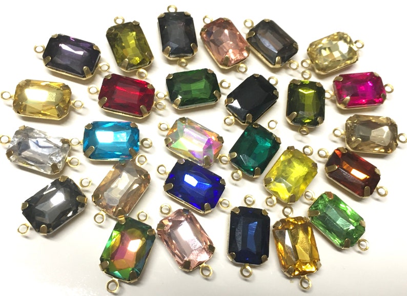May include: Assortment of colorful glass rectangular beads with gold metal loops on each end. The beads are in various colors, including red, blue, green, yellow, and clear.