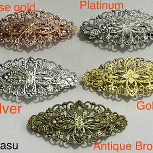 Könnte beinhalten: Fünf Haarspangen aus Filigran in Roségold, Platin, Silber, Gold und Antikbronze. Jede Spange hat ein florales Design. Der Markenname "Mytasu" steht unten.