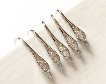 May include: Five silver-toned earring hooks with clear crystal accents. Each hook has a teardrop shape with three small crystals.