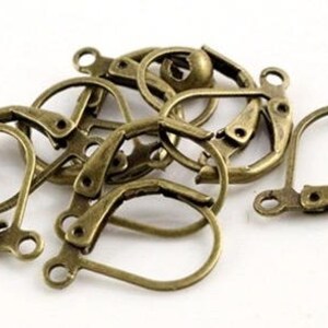 May include: A close-up of a group of antique gold-toned earring hooks. The hooks are made of metal and have a spring-loaded clasp.