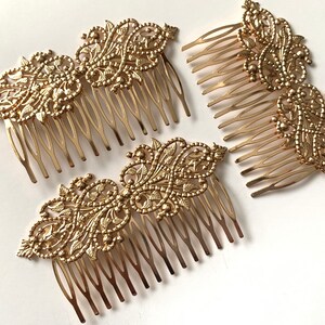 May include: Three gold hair combs with intricate filigree designs. Each comb has a decorative floral pattern and a row of teeth.