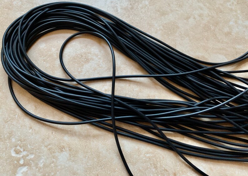 May include: A close-up of a large bundle of black elastic cord. The cord is tightly wound and appears to be made of a durable material.