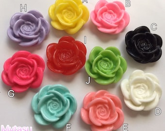 Op de afbeelding: Tien verschillende gekleurde hars rozenbloem versieringen. De bloemen zijn in verschillende kleuren, waaronder roze, rood, groen, geel, zwart, wit en blauw.