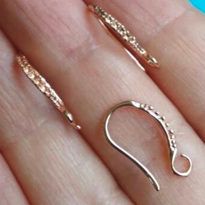 May include: Two gold-toned earring hooks with a textured surface. The hooks are designed to be used with jewelry making supplies.