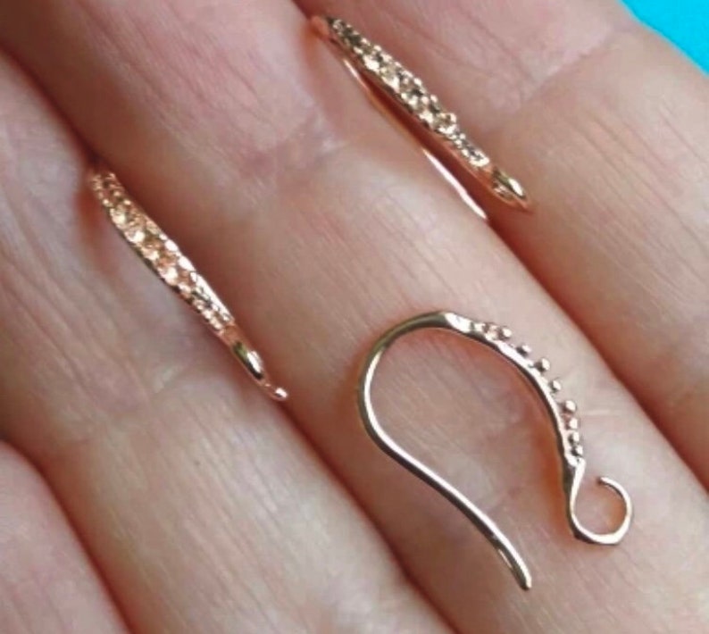 May include: Two gold-toned earring hooks with a textured surface. The hooks are designed to be used with jewelry making supplies.