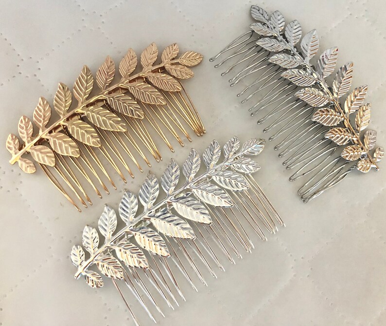 Op de afbeelding: Drie gouden en zilveren haar kammen met een bladontwerp. De kammen zijn gemaakt van metaal en hebben een delicate, vrouwelijke uitstraling.