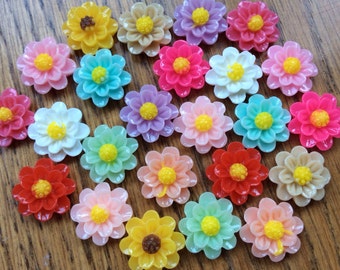 Könnte beinhalten: Sortiment an bunten, blumenförmigen Harz-Cabochons. Die Cabochons sind in verschiedenen Farben, darunter rosa, gelb, blau, grün und weiß. Sie haben alle einen Durchmesser von etwa 2,5 cm.