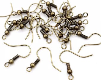 May include: A close-up of a pile of gold-toned earring hooks with spring-loaded clasps. The hooks are made of metal and have a smooth, polished finish.