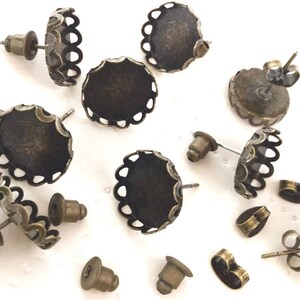 May include: A collection of 10 antique bronze earring settings with scalloped edges. The settings are designed to hold a small round cabochon.